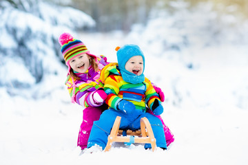 Kids on sleigh ride. Children sledding. Winter snow fun.