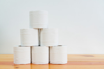 White tissues paper or toilet paper on wooden table over white wall.