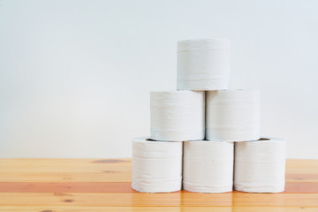 White tissues paper or toilet paper on wooden table over white wall.