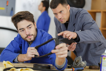 two mechanics working on a car part