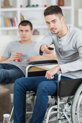 young handicapped man watching television with friend