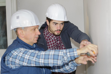 two working builders applies glue on a wall