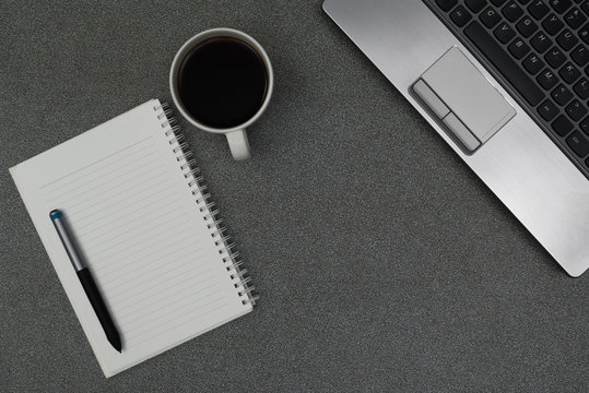 Laptop computer or notebook, note and cup of coffee on working table with copy space top view.