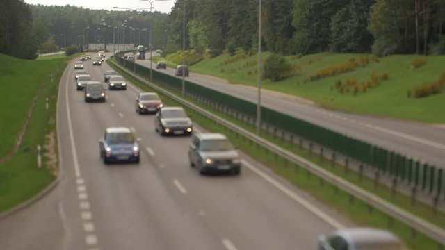 Cars running on highway down street. Four lanes two direction. Vilnius transport traffic. Blurry image.