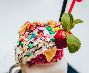 Glass of strawberry milkshake with whipped cream and fresh strawberries