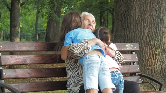 Happy elderly woman hugging children. Grandmother hugs her granddaughters.