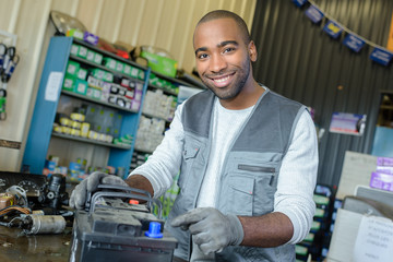 male mechanic with used vehicle battery on shop counter