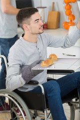 young man in wheelchair opens the oven to prepare food