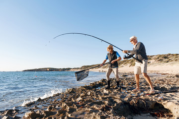 Senior man fishing with his grandson