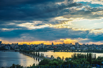 Fototapeta premium Dramatic sunset and dark clouds over right bank of Voronezh, Chernavsky bridge over water reservoir 