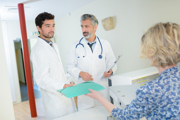 Obraz premium woman behind the reception desk giving folder to doctors