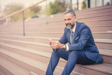 Senior businessman relaxing in an urban area, having a break from work