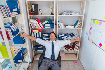 Businessman working in the office with piles of books and papers