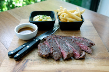 Grilled beef steak on cutting board and with pepper sauce
