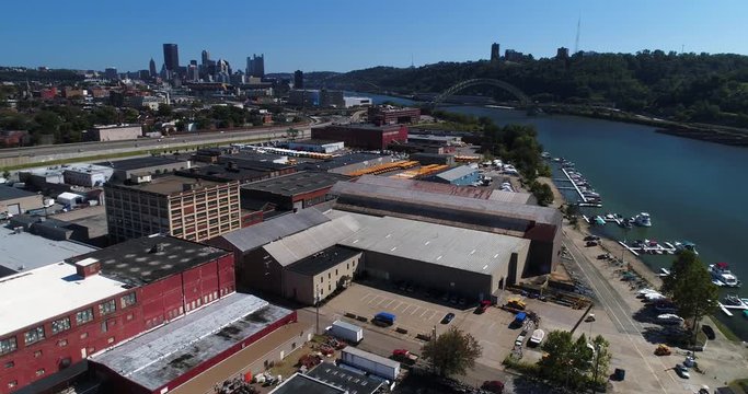 A mid-day slow forward aerial establishing shot of the Pittsburgh skyline with the warehouse business industrial park in the foreground.  	