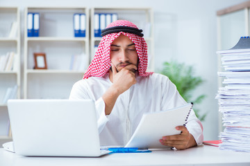 Arab businessman working in the office doing paperwork with a pi