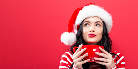 Happy young woman with Santa hat drinking coffee