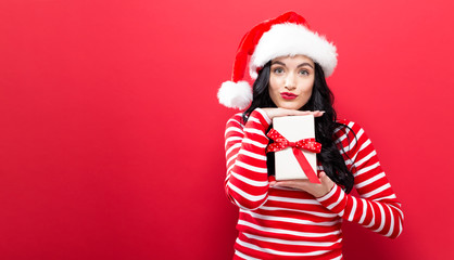 Young woman with Santa hat holding a Christmas present