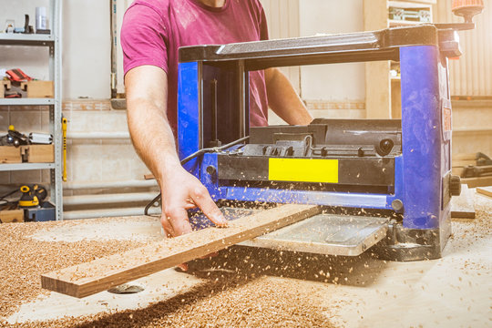man scouring a wooden board on an thicknessing machine