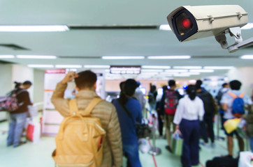CCTV security indoor camera system operating in airport with people queue at immigration control...