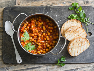 Tomato sauce braised chickpeas in a pot, and grilled bread. Delicious vegetarian lunch on a rustic...