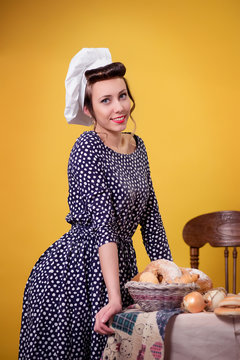 Girl in pin-up style  rests his hands on the table with bread rolls