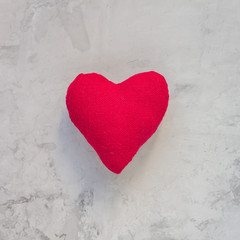 Handmade textile red heart on gray concrete background, square format