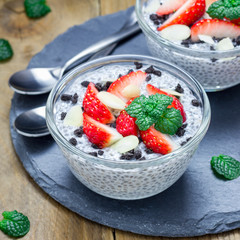 Chia seed pudding with strawberries, almond and chocolate cookie crumbs, on slate board, square format