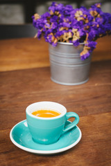 Espresso coffee cup on wooden table with violet flower.