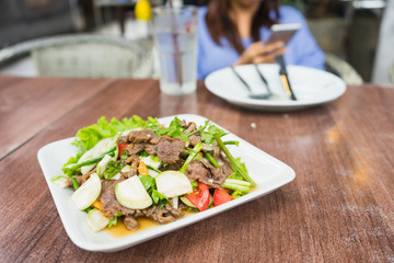 Spicy salad of roasted beef with blurred woman on background.
