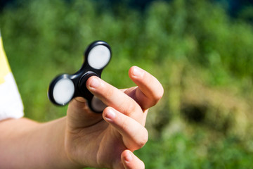 Boy playing with fidget spinner stress relieving toy outdoor