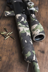 Small caliber 22 long rifle with an optical sight and cartridges in camouflage tape