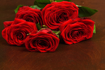 Bouquet of beautiful red roses on a dark wooden background closeup