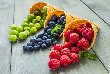 Berries. Raspberries, blackberries, blueberries in waffle cones on a wodden background. Healthy food concept