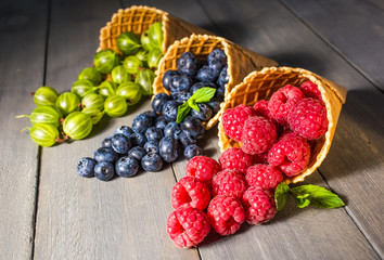 Berries. Raspberries, blackberries, blueberries in waffle cones on a wodden background. Healthy food concept