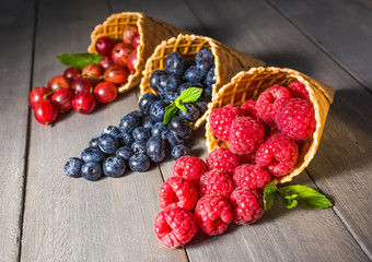 Berries. Raspberries, blackberries, blueberries in waffle cones on a wodden background. Healthy food concept