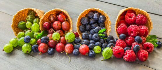 Berries. Raspberries, blackberries, blueberries in waffle cones on a wodden background. Healthy...
