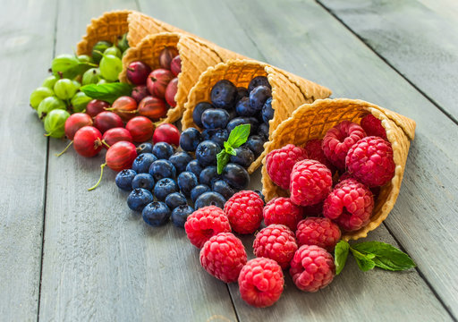 Berries. Raspberries, blackberries, blueberries in waffle cones on a wodden background. Healthy food concept