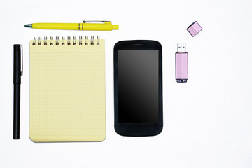 Fototapeta na wymiar A yellow notepad, a phone and a flash card.