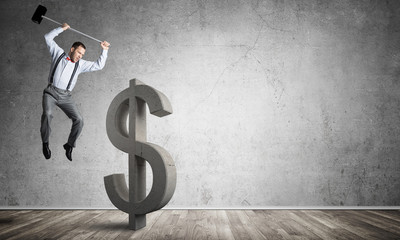 Determined banker man in empty concrete room breaking dollar figure