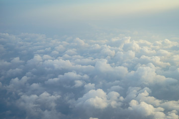 View of beautiful dreamy fluffy abstract white cloud with blue sky and sunrise light background from airplane window