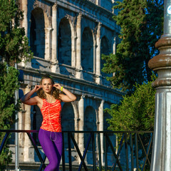 active woman near Colosseum in Rome, Italy listening to music