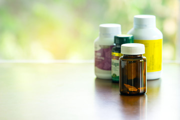  Bottles of medicine, vitamin and supplementary food on table with soft light and green bokeh background
