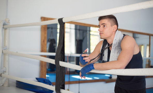 Coach watches the ring in the gym for boxing. Man watches the time on the stopwatch.