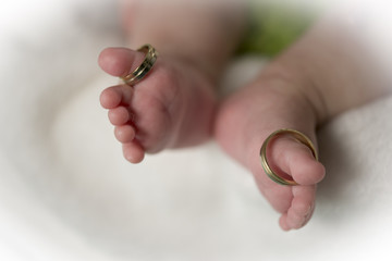 Beautiful conceptual image of  feet weeding rings put on baby feet fingers