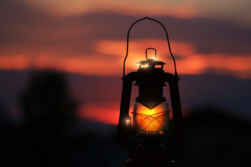 Burning lantern illuminated by and orange sunset © Alaskajade