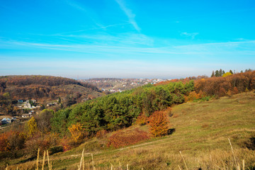 Naklejka premium View on the beautiful colorful autumn landscape of the hills with trees and greenfields in the countryside