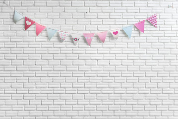 White brick wall decorated by colorful and pink cartoon flags for children or baby shower party