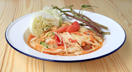 Papaya Salad with Carrot, Lentils, Tomato, Dried Shrimp, Chilli, in a White plate on wooden background. Thai style food.