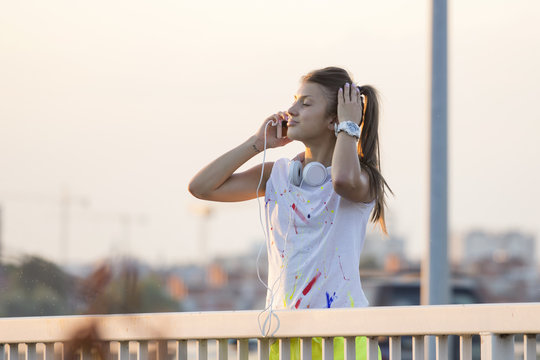 Girl tolking on mobile phone at bridge after jogging at sunset
